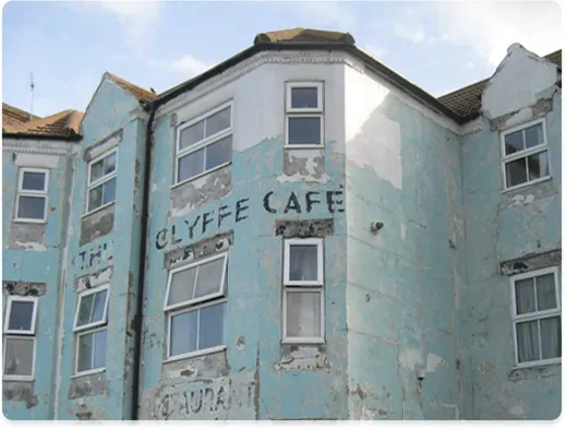 An external shot of a run down building with peeling paint and cracked plaster
