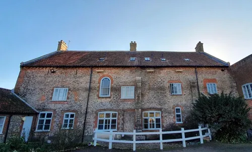 Exterior shot of an old country home with ornate windows and a scupture in the garden
